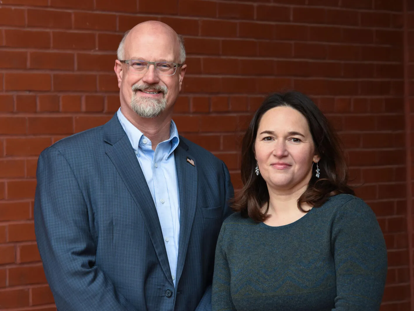 Mark Higgins and Amber Concepcion standing together in front of a brick wall.