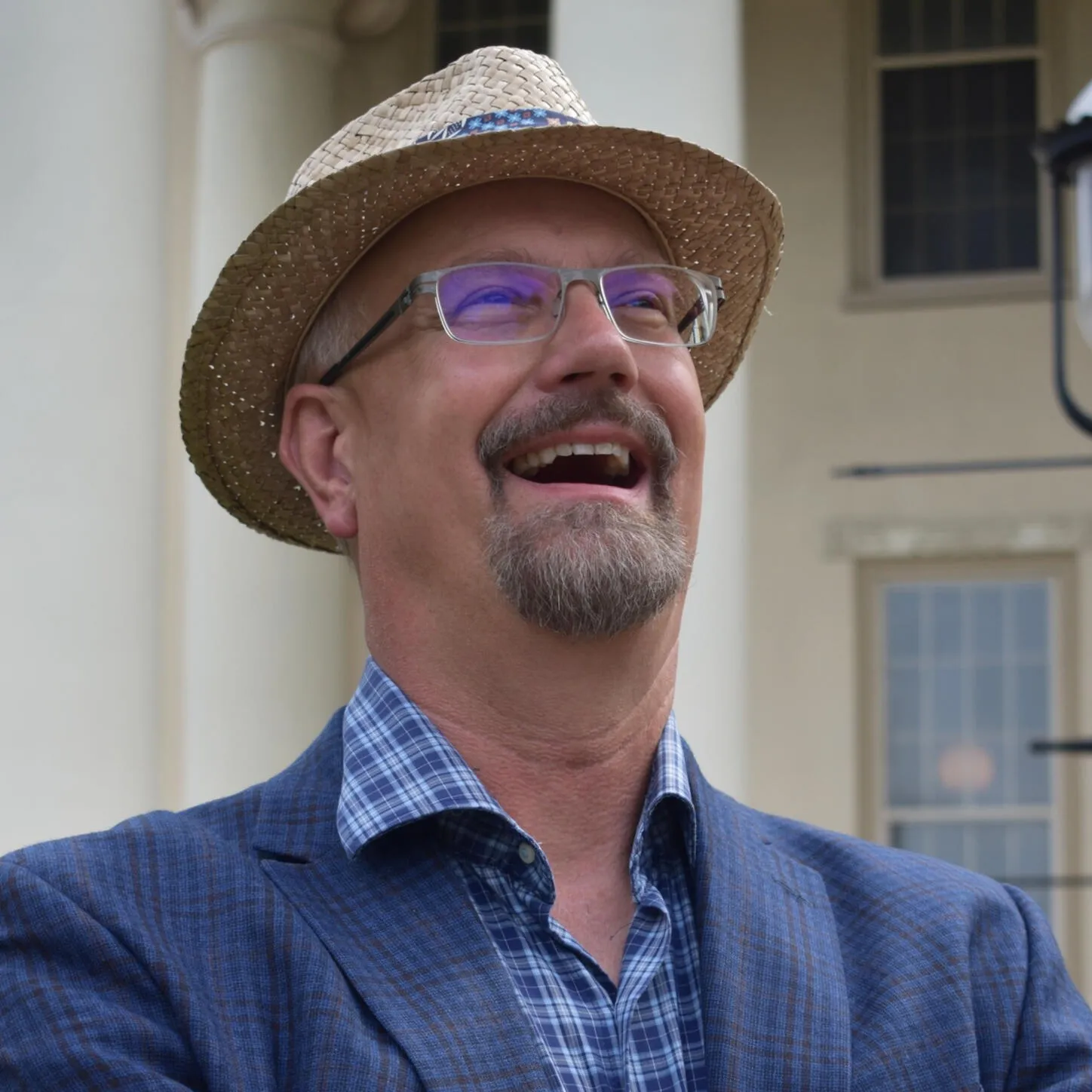 Mark Higgins smiling outdoors in a straw hat.